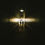 two person walking between concrete walls