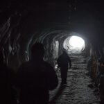 silhouette of three person walking inside tunnel